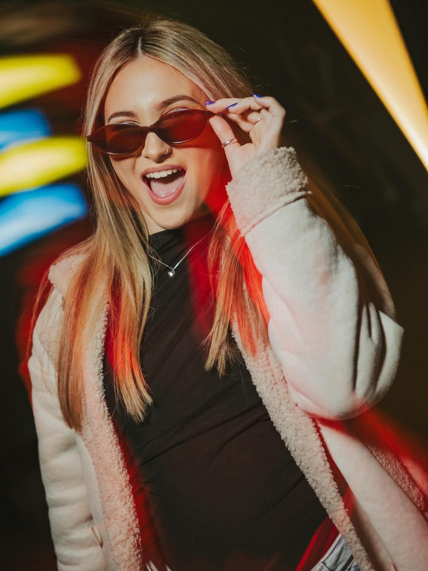Chica con gafas de sol bajo los neones de Fanático